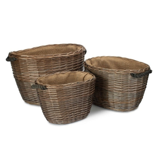 Three oval wicker log baskets with hessian lining displayed together on plain blank background