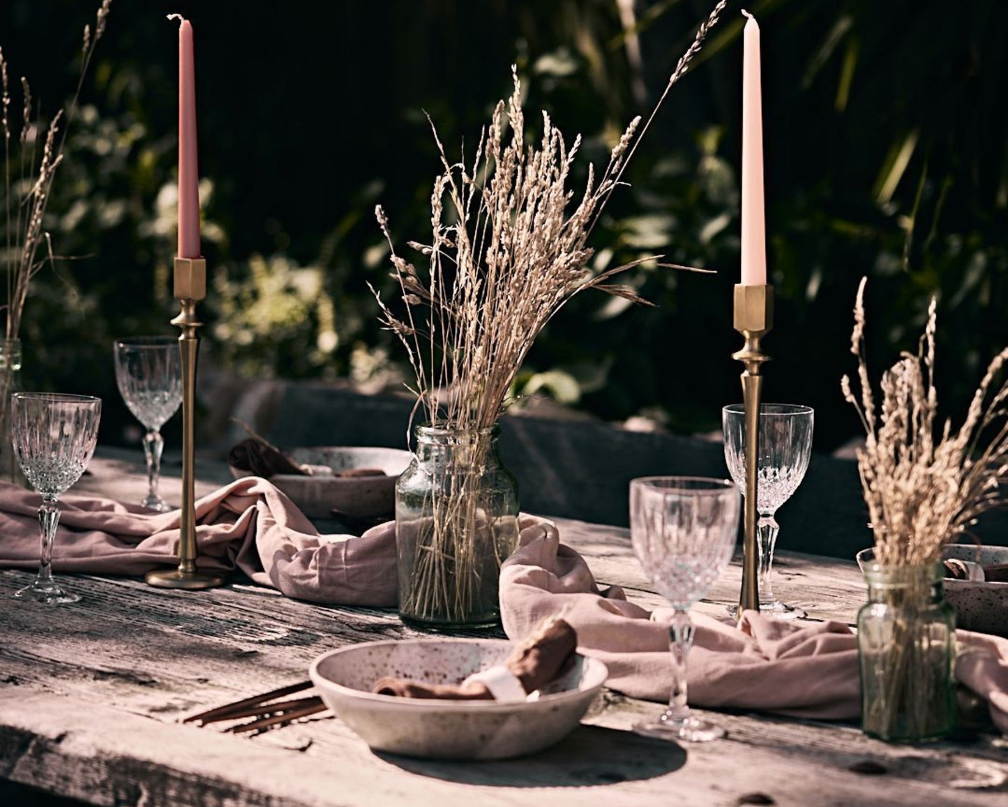 Brass candle holders displayed on an outdoor rustic wedding table set for a formal country celebration.