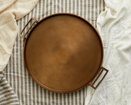 Brontë bronze round serving tray 35cm with geometric handles styled on striped linen, hand-finished UK