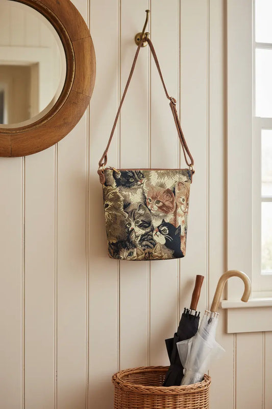 Cat tapestry sling bag hanging on brass hook in cottage hallway entryway UK