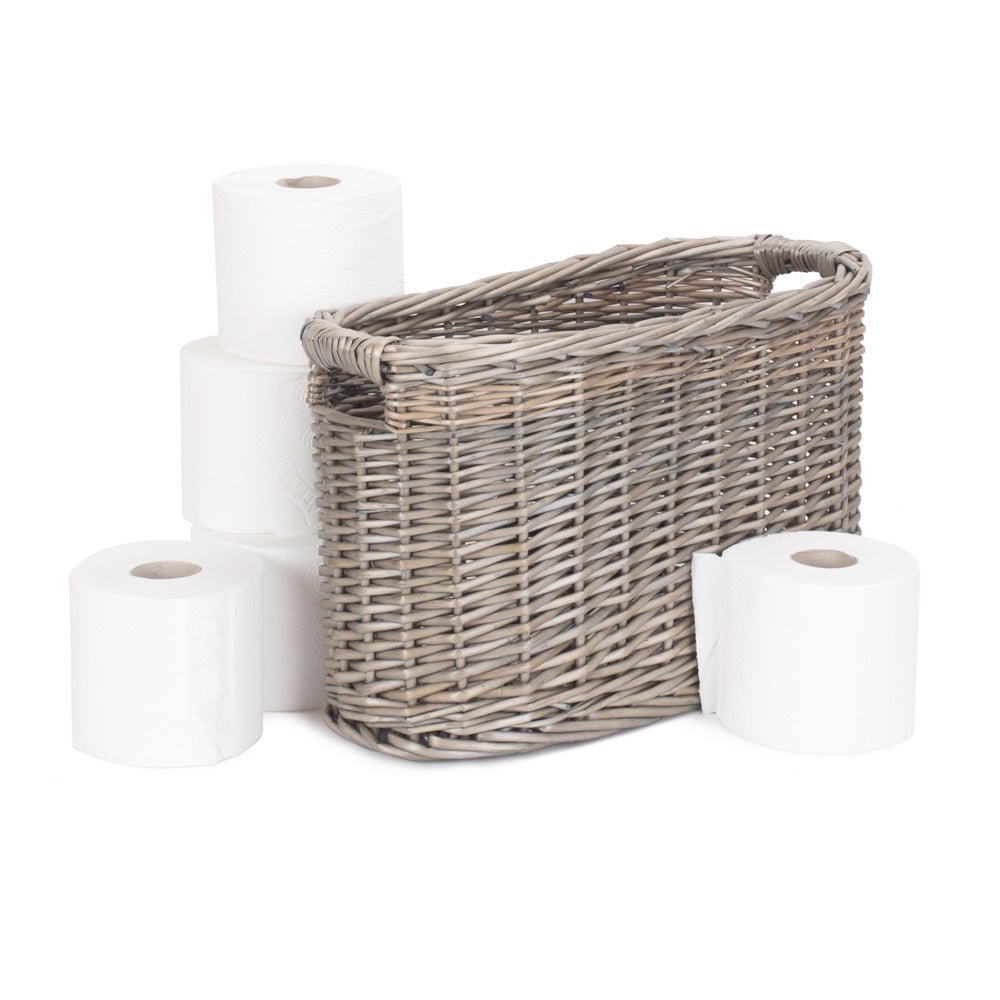 Handwoven oval wicker loo basket styled with five toilet rolls beside it – heritage-inspired bathroom storage with natural charm