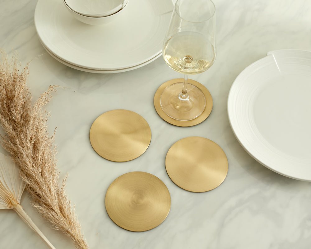 Hawthorn brass coasters set of 4 styled on marble table with glass and white plates