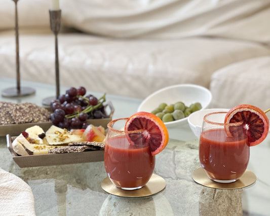 Hawthorn brass coasters set of 4 styled with cocktail glasses and snacks on table