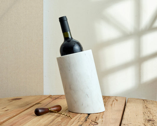 Winsford marble wine holder, white stone wine bottle stand, styled on a table with a corkscrew