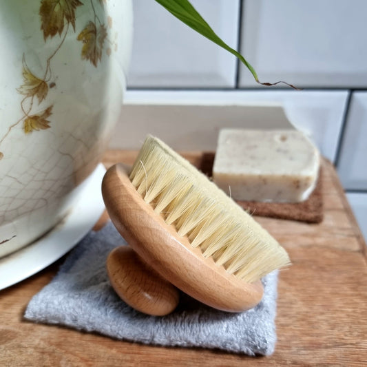 Natural wooden body brush and vegan soap on vanity with rustic styling and soft countryside tones