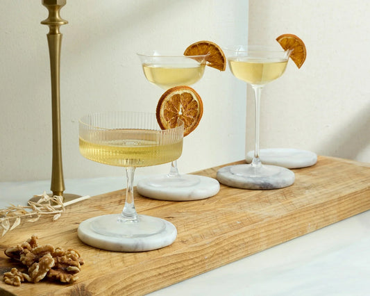 Cocktail glasses dried orange garnishes round marble coasters wooden board heritage UK