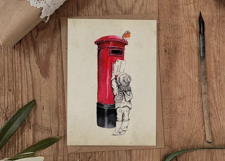 Child posting Christmas card letter to Santa in red postbox UK countryside festive tradition heritage moment