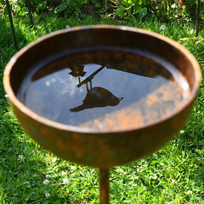 Rusty rain catcher birdbath garden sculpture stakes cottage garden British countryside UK 