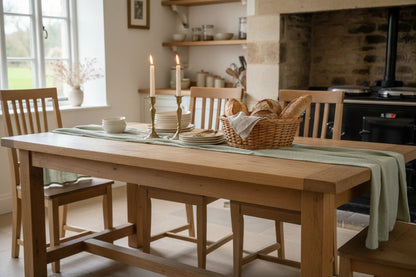 Willow green muslin cotton table runner 250cm styled on farmhouse dining table with brass candlesticks cottage kitchen UK