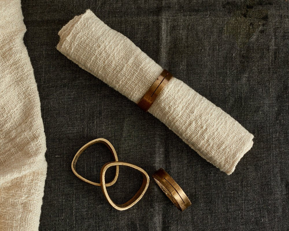 Agnes brass napkin rings set of 4 handcrafted table accents looking down view with napkin in one ring
