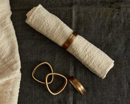 Agnes brass napkin rings set of 4 handcrafted table accents looking down view with napkin in one ring
