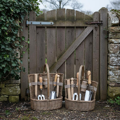 Antique wash willow garden baskets with tools beside weathered garden gate UK