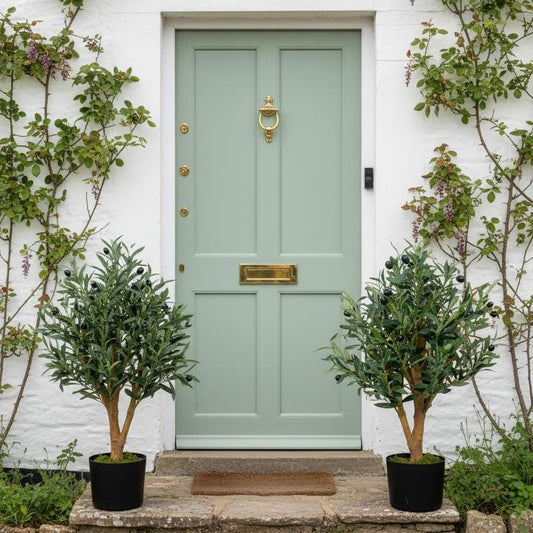 Two 65cm artificial olive trees flanking heritage cottage door entrance for symmetrical styling