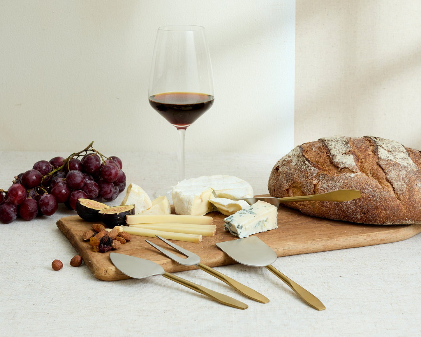 Edith cheese cutlery set 4 piece stainless steel serving set styled with cheeses nuts bread grapes and wine

