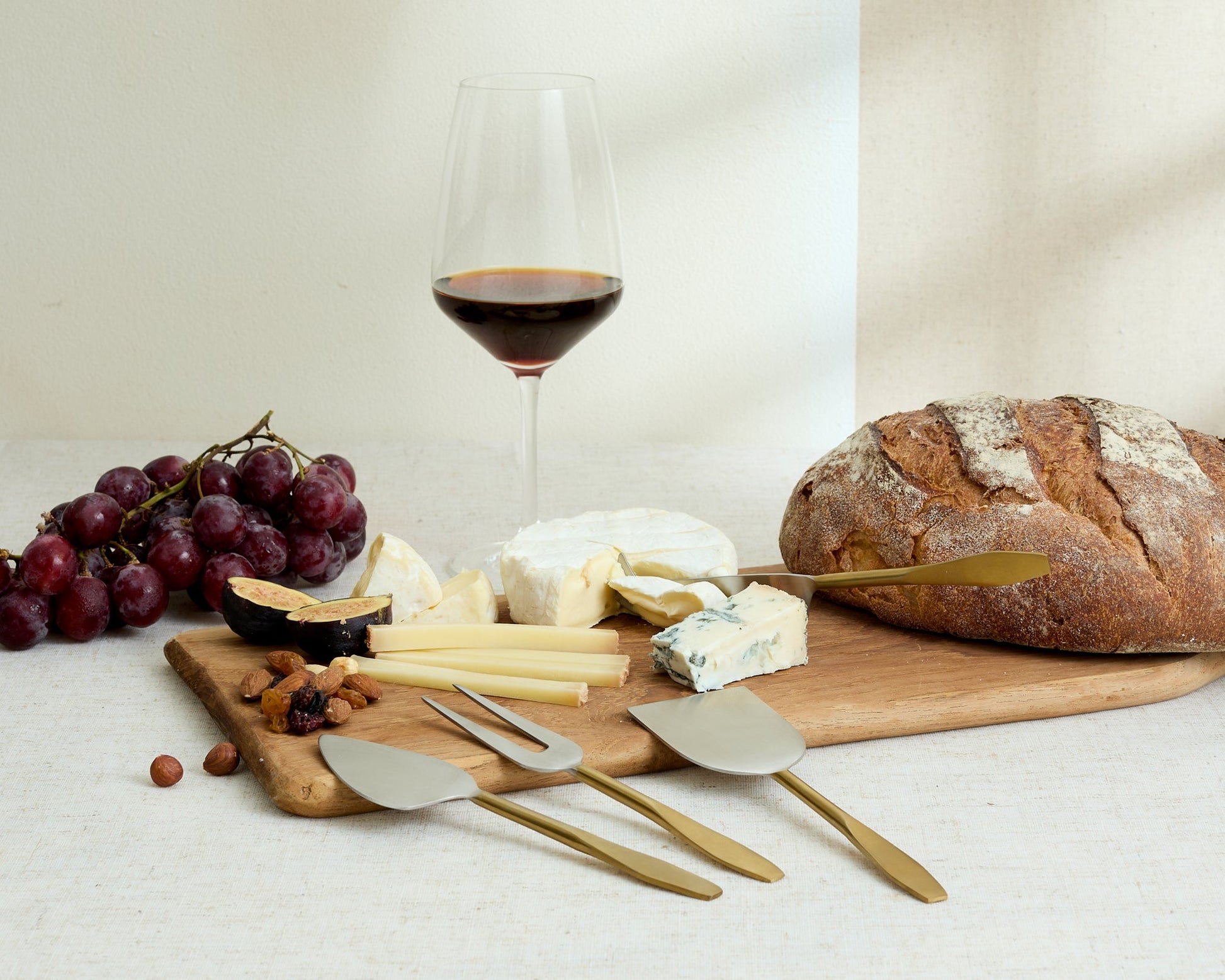Edith cheese cutlery set 4 piece stainless steel serving set styled with cheeses nuts bread grapes and wine
