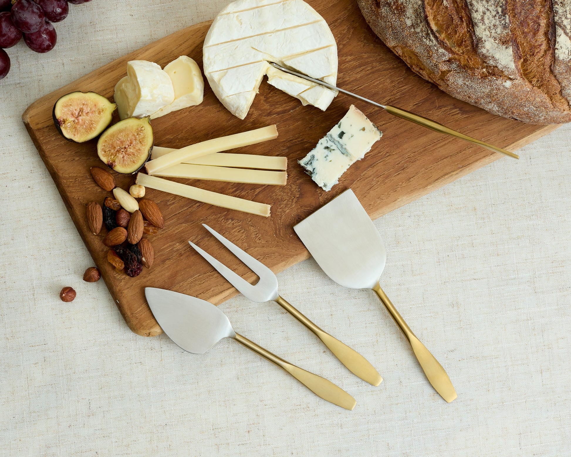 Edith cheese cutlery set 4 piece stainless steel serving set styled with cheeses nuts and bread on table
