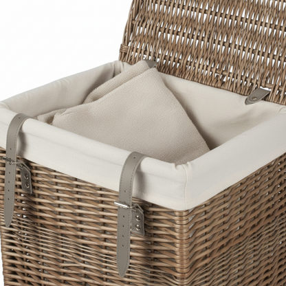 Close-up rectangular laundry basket handwoven willow antique wash with leather buckle straps and cotton lining