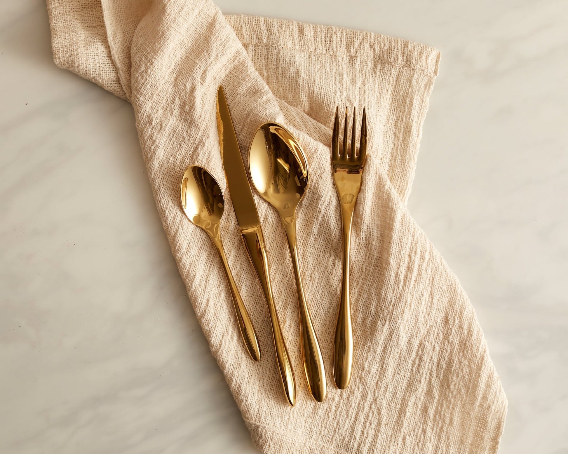 Gold stainless steel cutlery set heritage flatware on linen napkin UK