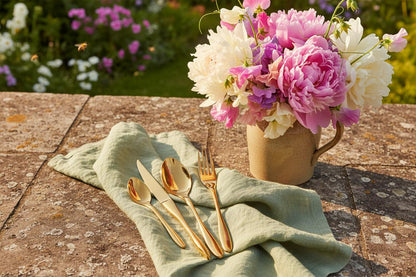 Gold cutlery set on stone terrace with peonies cottage garden summer UK