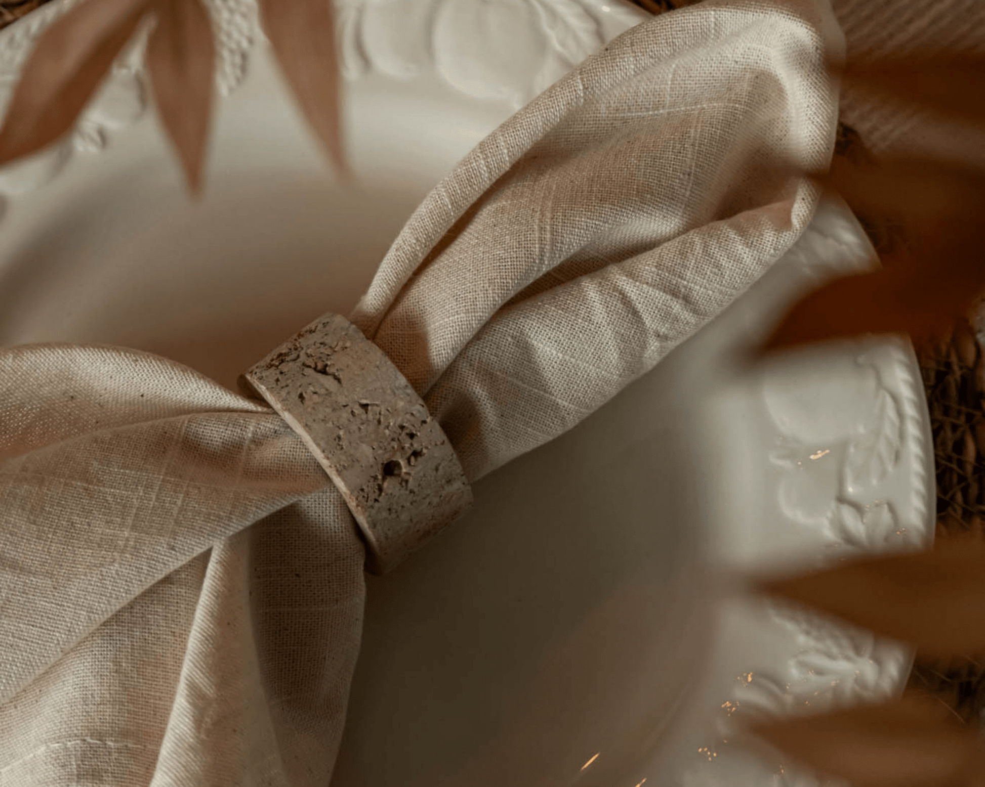 Langley travertine napkin rings set of 4 artisan stone accents styled with linen napkin on plate
