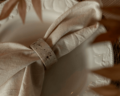 Langley travertine napkin rings set of 4 artisan stone accents styled with linen napkin on plate
