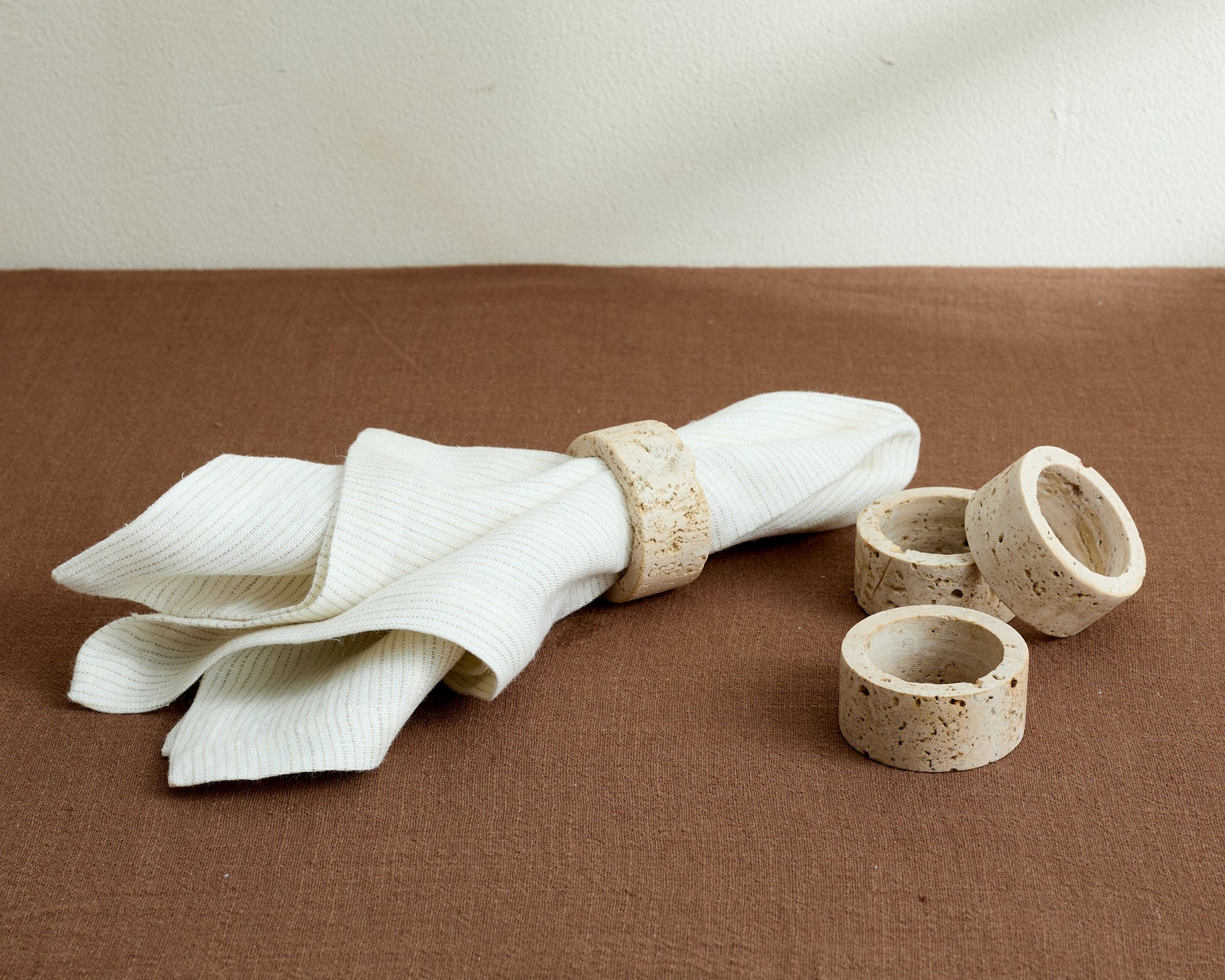 Langley travertine napkin rings set of 4 artisan stone accents on table with one napkin in ring
