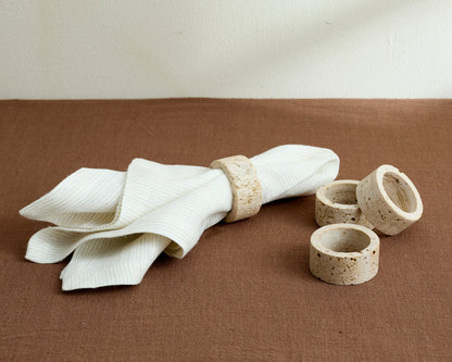 Langley travertine napkin rings set of 4 artisan stone accents on table with one napkin in ring
