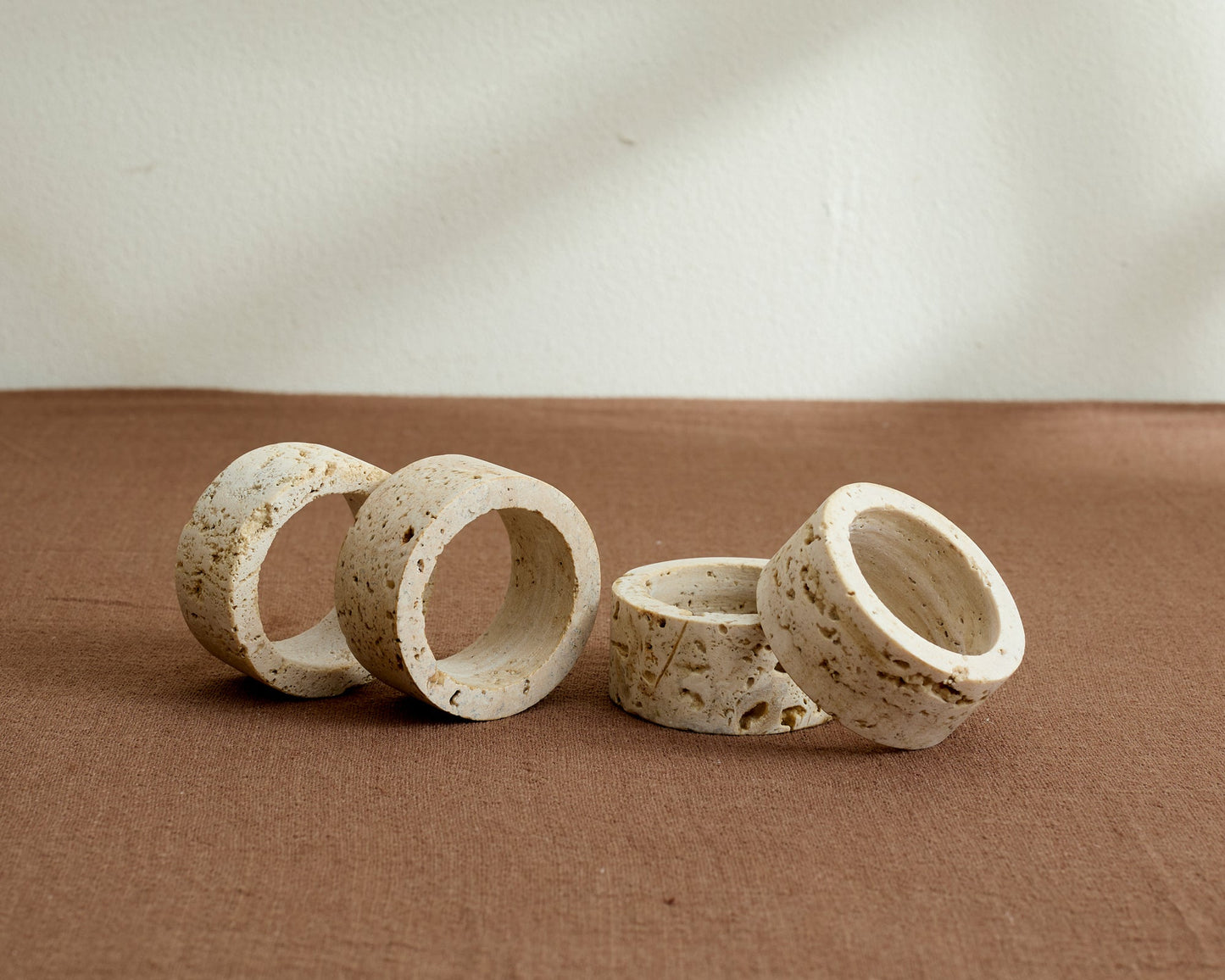 Langley travertine napkin rings set of 4 artisan stone table accents displayed on table top
