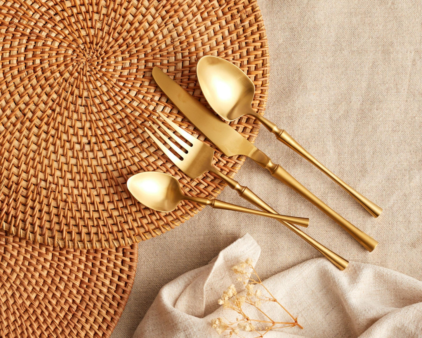 Matte gold stainless steel cutlery set styled on woven placemat UK
