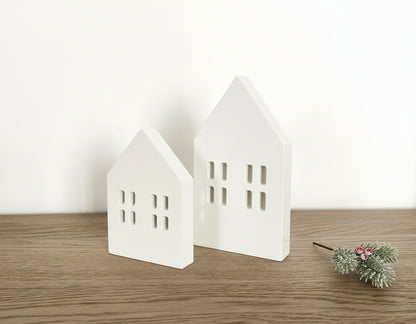 Scandi wooden Christmas village houses Nordic decoration on wooden mantle with festive sprigs
