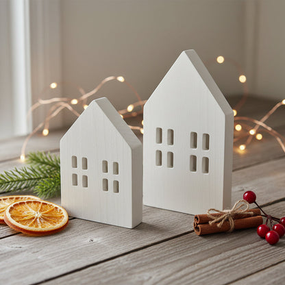 Scandi wooden Christmas village houses Nordic decoration on wooden table with festive sprigs
