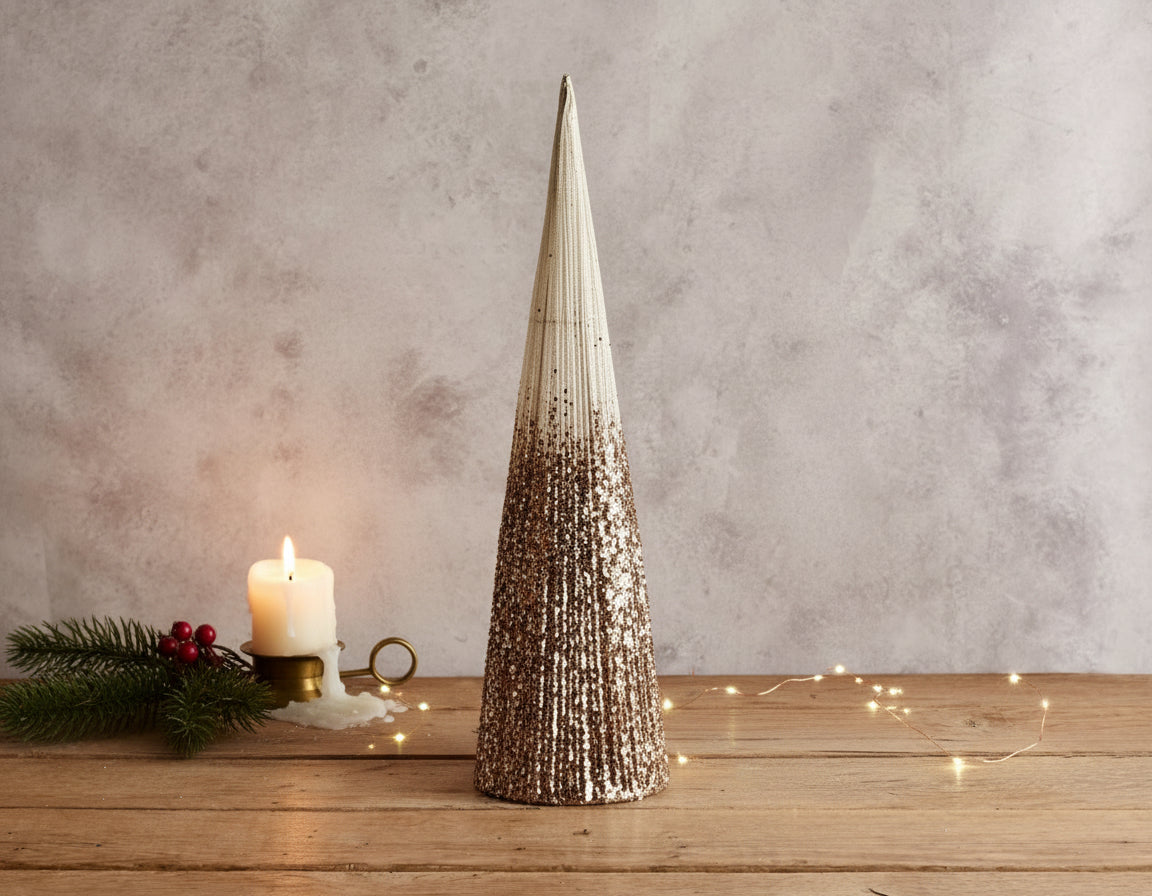 Snowed Christmas cone tree festive mantel decoration on wooden table with candle and sprig
