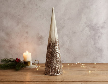 Snowed Christmas cone tree festive mantel decoration on wooden table with candle and sprig
