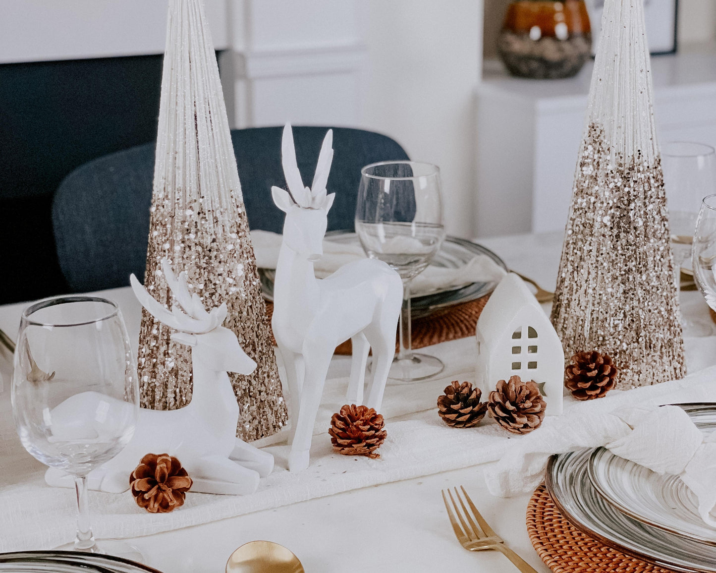Two snowed Christmas cone trees festive mantel decorations on tablescape with seasonal styling
