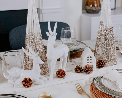 Two snowed Christmas cone trees festive mantel decorations on tablescape with seasonal styling
