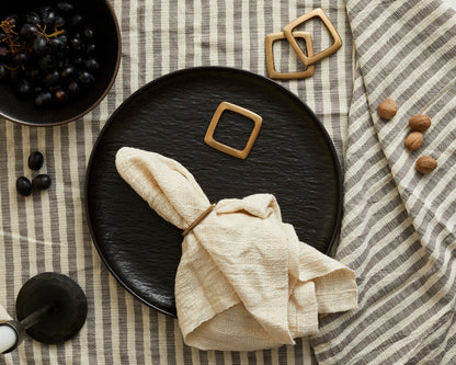 Trafalgar brass napkin ring on natural napkin with linen stripe cloth and black plates