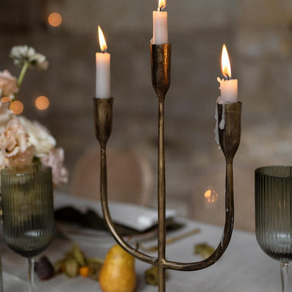 Close view of Weldon gold iron trident candelabra with three taper candles highlighting craftsmanship