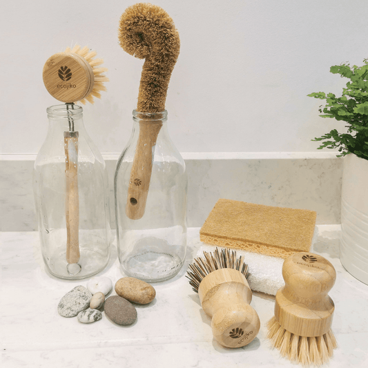 Eco wooden dish brush gift set styled in rustic kitchen with bamboo brush, cloth and sponge on ceramic sink or wooden counter